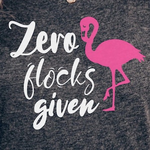 Puede incluir: Una camiseta gris oscuro con el texto "Zero flocks given" en letras blancas y un gráfico de flamenco rosa.