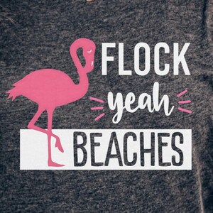 Könnte beinhalten: Ein dunkelgraues T-Shirt mit einem pinkfarbenen Flamingo-Motiv und dem Text "FLOCK yeah BEACHES".