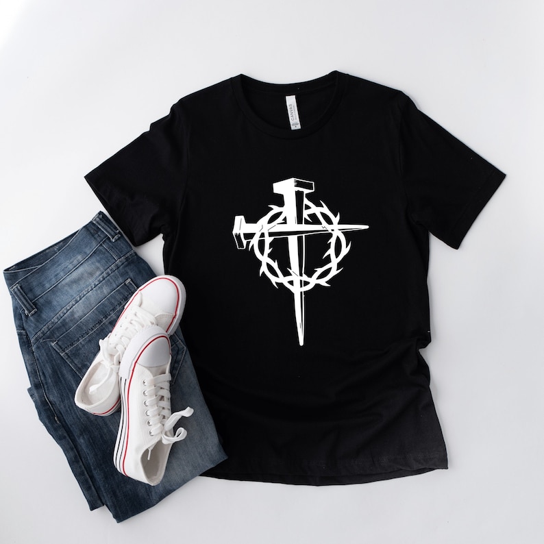 May include: A black t-shirt with a white graphic of a cross with nails and a crown of thorns.