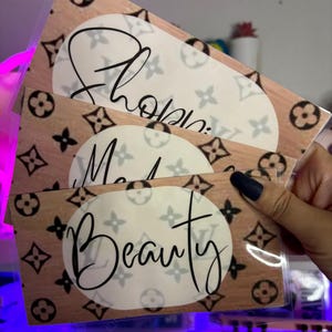 May include: Three brown and white patterned cards with the words "Shop", "Make Up", and "Beauty" written in black cursive.