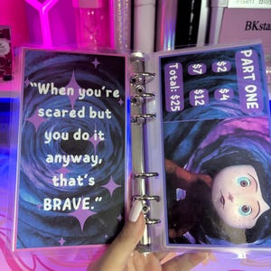 May include: A clear plastic binder with a blue and purple background. The binder has a quote that reads "When you're scared but you do it anyway, that's BRAVE." The binder also has a picture of a character from the movie "The Nightmare Before Christmas".