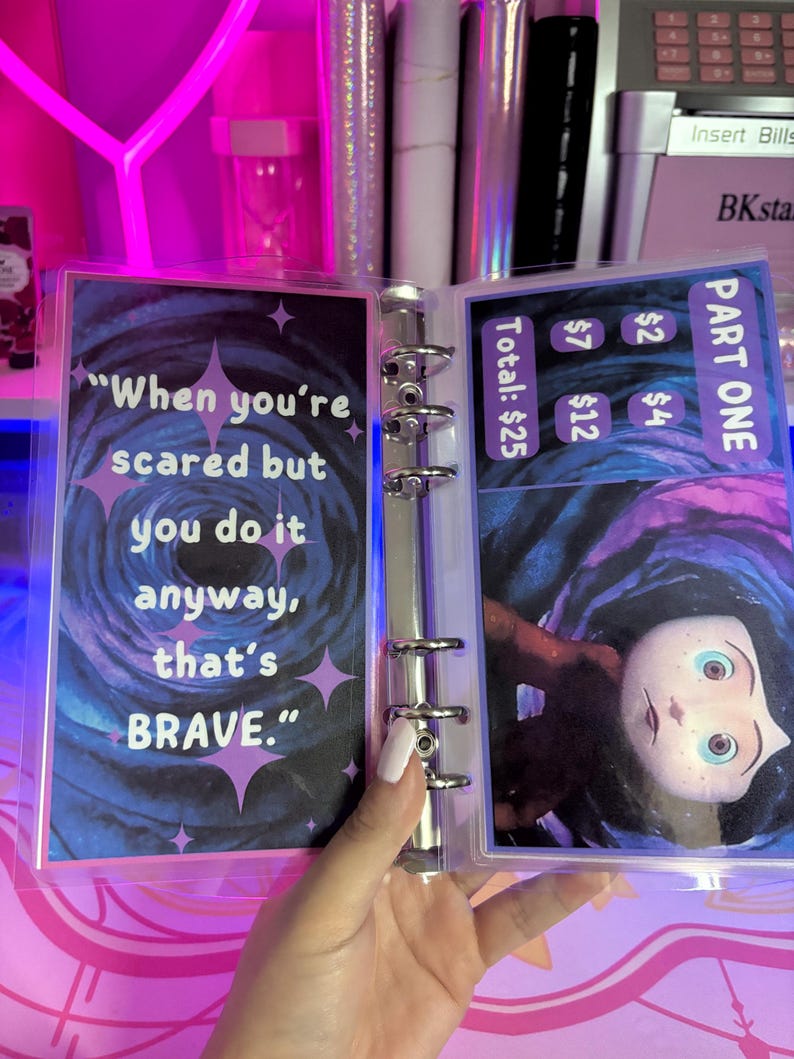 May include: A clear plastic binder with a blue and purple background. The binder has a quote that reads "When you're scared but you do it anyway, that's BRAVE." The binder also has a picture of a character from the movie "The Nightmare Before Christmas".