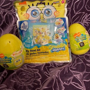 May include: A SpongeBob Squarepants themed bead kit with a yellow plastic egg containing 44 tattoos. The bead kit includes a variety of colorful beads, a bead board, and an iron-on design. The kit is packaged in a clear plastic bag with a SpongeBob Squarepants character on the front.