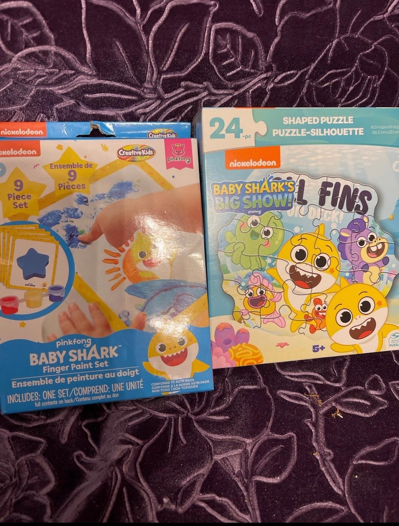 May include: A set of two Baby Shark themed toys. The first is a 9-piece finger paint set with a blue, yellow, and orange color scheme. The second is a 24-piece shaped puzzle featuring Baby Shark and friends.