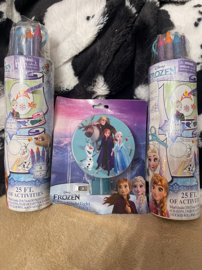 May include: Two cylindrical activity sets and a nightlight featuring characters from Disney's Frozen. The activity sets include crayons and a sticker roll with 25 feet of printed pages. The nightlight has a round design with the Frozen characters.