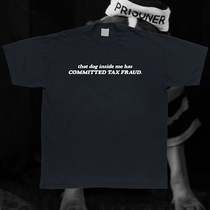 May include: A dark blue t-shirt with white text that reads "that dog inside me has COMMITTED TAX FRAUD."