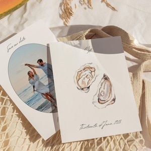 May include: Two wedding announcement cards. One features a couple dancing on a beach, with the text "save our date." The other card has watercolor oyster illustrations and the text "Thirteenth of June, 2026."