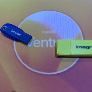Puede incluir: Dos unidades flash USB, una azul con el texto "SanDisk" y otra amarilla con el texto "integral".