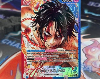 May include: A collectible trading card featuring a character with black hair and facial markings. The card has a blue border with the number 6000 and the word "SPECIAL". Text on the card includes "Portgas.D. Ace" and "Whitebeard Pirates".