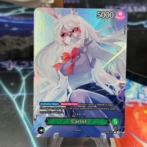 Puede incluir: Una tarjeta coleccionable con un personaje de estilo anime con cabello blanco, orejas de conejo y un lazo rojo. La tarjeta tiene el nombre "Carrot" y un valor de "5000". Es una tarjeta "Especial" con un valor de vida de 5.