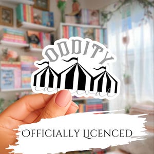 May include: A die-cut sticker featuring a black and white striped carnival tent graphic. The word ODDITY is printed in a bold, grey, arched font above the tent, and the word carnival is written in a cursive, grey script below the tent.