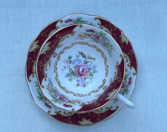 May include: A vintage teacup and saucer set with a floral pattern and gold trim. The cup and saucer are both decorated with a burgundy and gold design.