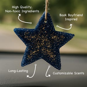 May include: A dark blue star-shaped car air freshener with gold glitter detailing, suspended by a twine string. The image text includes "High Quality, Non-toxic Ingredients", "Book Boyfriend Inspired", "Long-Lasting", and "Customizable Scents". The text at the bottom says "Your favorite High Lord, now in car-freshener form".