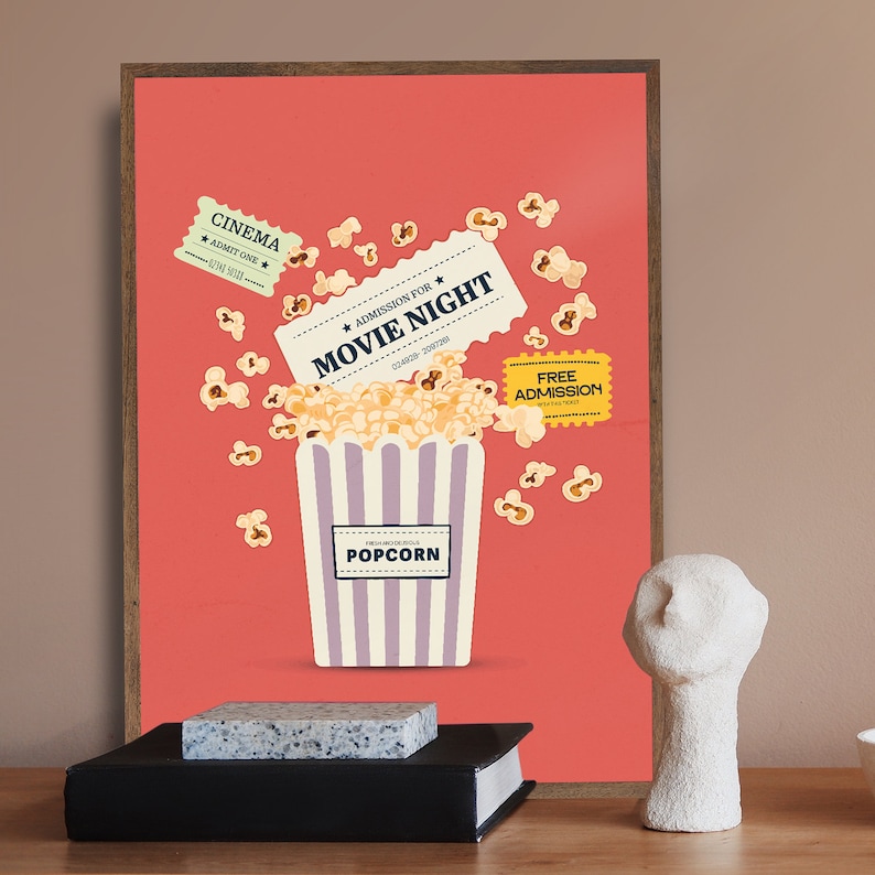 K&ouml;nnte beinhalten: Ein rotes Poster mit einem gestreiften Popcorn-Eimer und Kinokarten, auf denen "Admission for Movie Night" steht. Popcorn f&auml;llt aus dem Eimer. Das Poster ist in braunem Holz gerahmt.