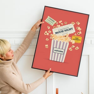 K&ouml;nnte beinhalten: Ein rotes Poster mit schwarzem Rahmen, das f&uuml;r einen Filmabend wirbt. Das Poster zeigt einen gestreiften Popcorn-Eimer, der &uuml;berquillt mit Popcorn und Tickets mit der Aufschrift "Kino" und "Eintritt f&uuml;r den Filmabend".