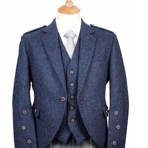 Puede incluir: Una chaqueta de tweed azul marino con un chaleco a juego y una falda escocesa. La chaqueta tiene cierre de doble botonadura y un bolsillo con botón en el lado izquierdo.