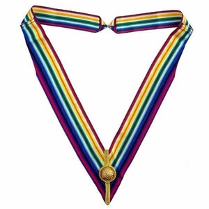 Puede incluir: Una corbata de rayas de colores con un botón dorado. La corbata tiene rayas de rojo, morado, azul, verde, amarillo y blanco.