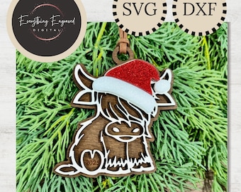 May include: Wooden Highland cow ornament wearing a Santa hat with red glitter and white trim. The ornament has a brown finish and the year 2025 is visible. The words "DIGITAL DOWNLOAD" are at the bottom.