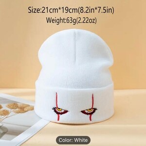 May include: White knit beanie with red embroidered eyes and red lines. Size: 21cm x 19cm (8.2in x 7.5in). Weight: 63g (2.22oz).
