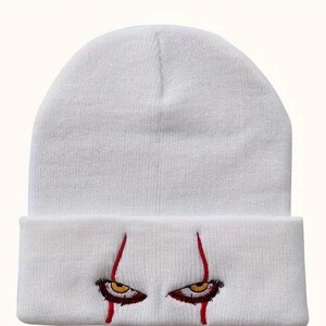 May include: White knit beanie with red embroidered eyes and blood dripping down the sides.