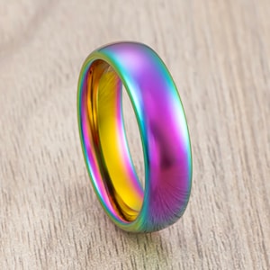 May include: A rainbow iridescent ring with a smooth, polished finish. The ring is made of metal and has a rounded shape.