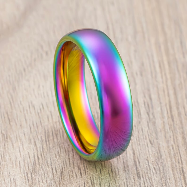 May include: A rainbow iridescent ring with a smooth, polished finish. The ring is made of metal and has a rounded shape.