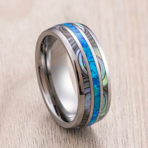May include: A silver tungsten carbide ring with a blue and white abalone shell inlay.