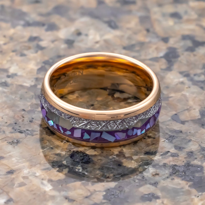 Puede incluir: Un anillo de oro y plata con una incrustaci&oacute;n de color p&uacute;rpura y blanco. El anillo tiene una banda texturizada y un acabado pulido.