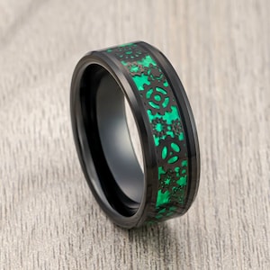 May include: Black tungsten carbide ring with a green inlay featuring a gear design.