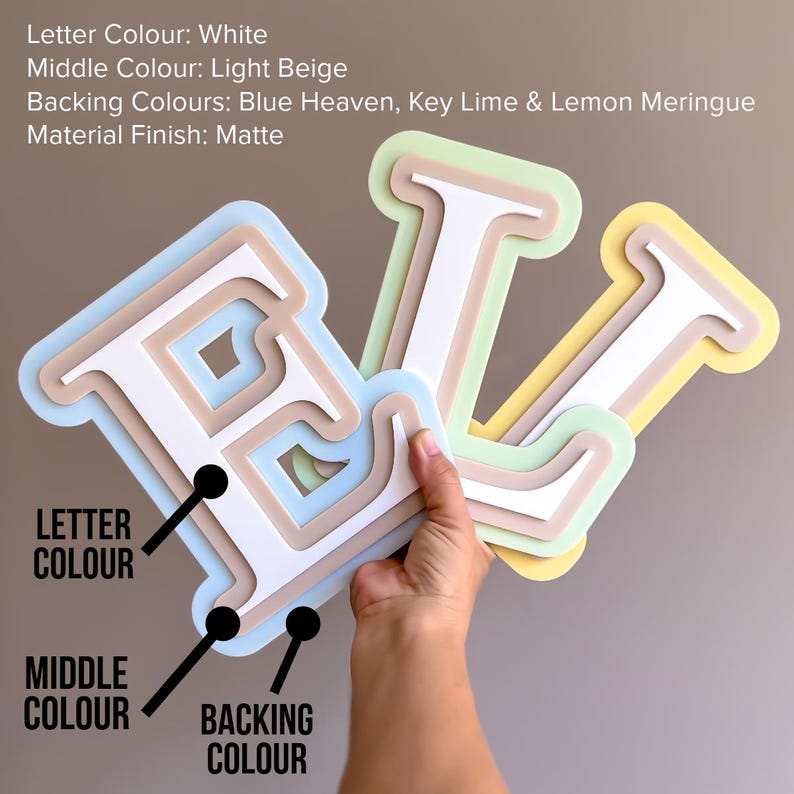 May include: Layered wooden letters spelling "E L V" in white, light beige, and pastel backing colors. The backing colors include blue, green, and yellow. The text on the image indicates the letter color is white, the middle color is light beige, and the backing colors are blue, green, and yellow.