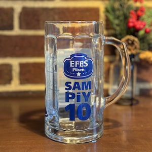 May include: A clear glass beer stein with a blue Efes Pilsen logo and the text "SAMPIY 10" in blue.