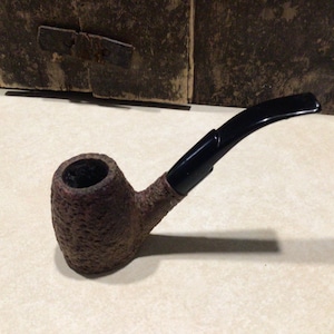 May include: A brown and black pipe with a textured bowl and a black stem.