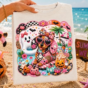 May include: A light-colored t-shirt featuring a colorful graphic of a dachshund wearing heart-shaped sunglasses and a bow, surrounded by tropical elements, pumpkins, and ghosts, with the text "SUMMER WEEN" visible on a wooden sign nearby.