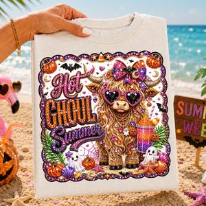 May include: A light-colored t-shirt featuring a graphic of a fluffy highland cow wearing heart-shaped sunglasses and a bow. The design includes the text "Hot GHOUL Summer" surrounded by pumpkins, ghosts, bats, and a colorful drink cup.