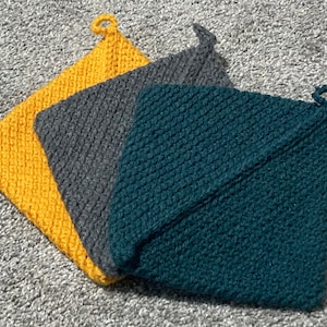May include: Three crocheted pot holders in yellow, gray, and teal. The pot holders are folded and stacked on top of each other.