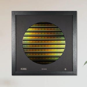 May include: A square black frame containing a circular display of a silicon wafer with a metallic, iridescent gold and green grid pattern. The black matting features small white text at the bottom, including the words Silicon Wafer.