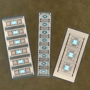 Può includere: Tre circuiti stampati rettangolari con tracce di rame e microchip blu. Le schede sono di dimensioni variabili e sono disposte su una superficie marrone. Le schede hanno un rivestimento protettivo trasparente.