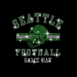 May include: Black graphic design with the words "SEATTLE FOOTBALL GAME DAY" in white and green rhinestones. A green football helmet and a green and white stripe are in the center of the design. The design has starburst accents.