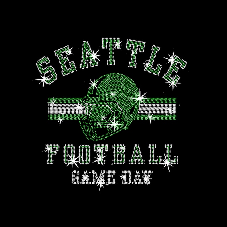May include: Black graphic design with the words "SEATTLE FOOTBALL GAME DAY" in white and green rhinestones. A green football helmet and a green and white stripe are in the center of the design. The design has starburst accents.