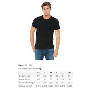 May include: A black crew neck t-shirt. The model is wearing the shirt with blue jeans. The product specifications table shows sizes XS to 5XL, with body length ranging from 27 to 32 inches and body width from 16.5 to 26 inches.