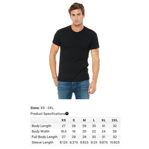 May include: A black crew neck t-shirt. The model is wearing the shirt with blue jeans. The product specifications table shows sizes from XS to 5XL, with measurements for body length, body width, full body length, and sleeve length in inches.