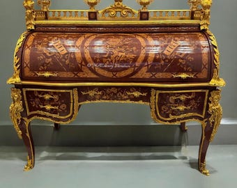 May include: A detailed shot of a roll-top desk. The desk is made of dark wood with intricate inlaid designs and gold accents. The desk features a curved roll-top, multiple drawers, and ornate carvings. The desk is a piece of luxury furniture.