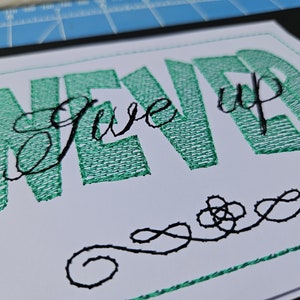 Puede incluir: Arte de pared bordado con el texto "Never Give Up" en hilo verde y un adorno decorativo negro.