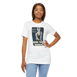 May include: White t-shirt with a retro graphic of a nurse and the words "AMERICA! Refuse to be quiet! NONE OF THIS IS NORMAL". The design is in blue and white.