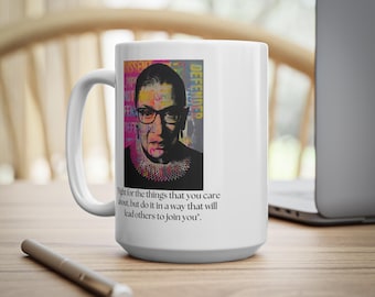 Puede incluir: Taza de cerámica blanca con un retrato de una mujer con gafas y un cuello negro. La taza tiene la palabra "DEFENDER" y una cita: "Lucha por las cosas que te importan, pero hazlo de una manera que lleve a otros a unirse a ti."