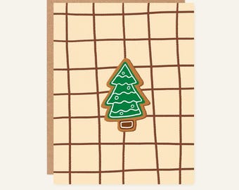 May include: A greeting card with a tan grid pattern background and a gingerbread Christmas tree design. The tree is green with white accents and a brown outline. The card is on a brown backing. The text "sonder studios" is at the bottom.