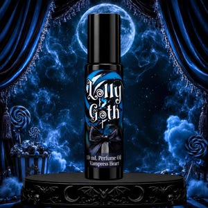 Puede incluir: Un frasco de aceite de perfume de 10 mL con tapa negra y una etiqueta con el texto Lolly Goth y Vampress Heart. La etiqueta muestra un patrón de remolinos azules y negros con un lazo negro. El frasco es cilíndrico y de vidrio transparente.
