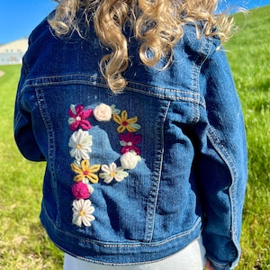 May include: A white ceramic mug with a black handle and the text "But First, Coffee" in a black, handwritten-style font. The mug is on a white surface.