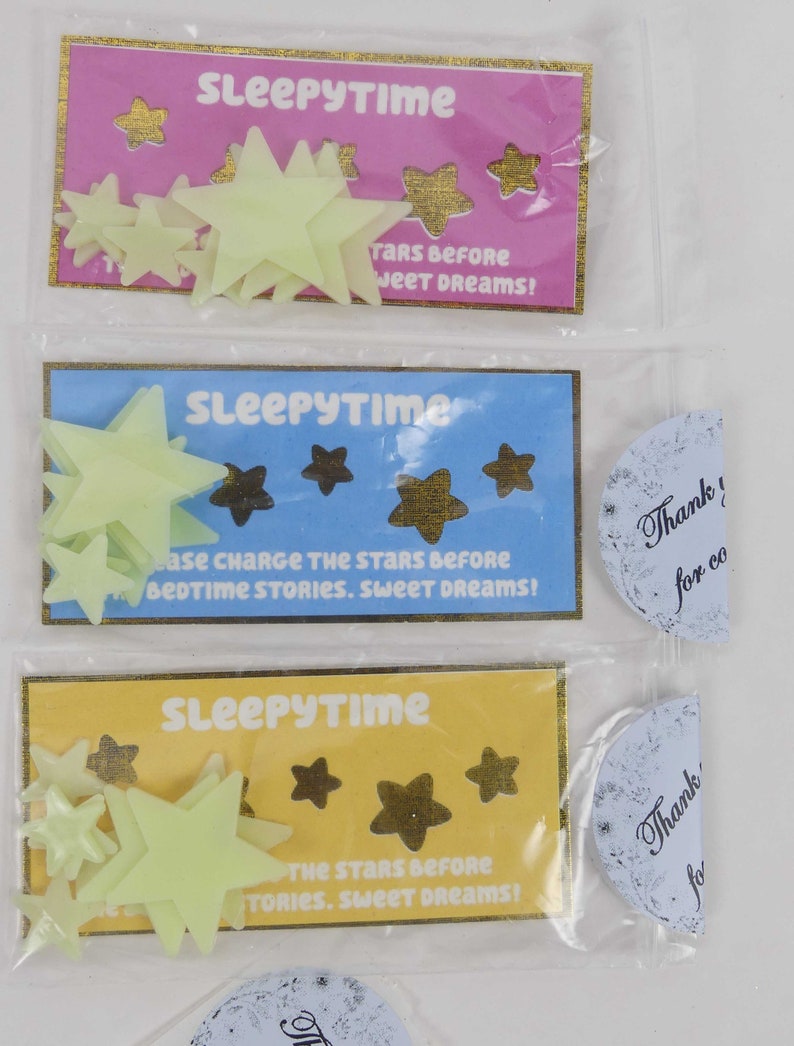 May include: Three packages of glow-in-the-dark stars for kids. Each package has a different colored background: pink, blue, and yellow. The packages say "Sleepytime" and have instructions to charge the stars before bedtime.