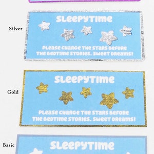 May include: Four blue cards with the text "SLEEPYTIME" and the words "PLEASE CHARGE THE STARS BEFORE THE BEDTIME STORIES. SWEET DREAMS!" The cards have different colored borders: rainbow, silver, gold, and basic.